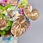 باقة ورد وردي وأخضر مع أنتوريوم ذهبي في فازة كريستالية